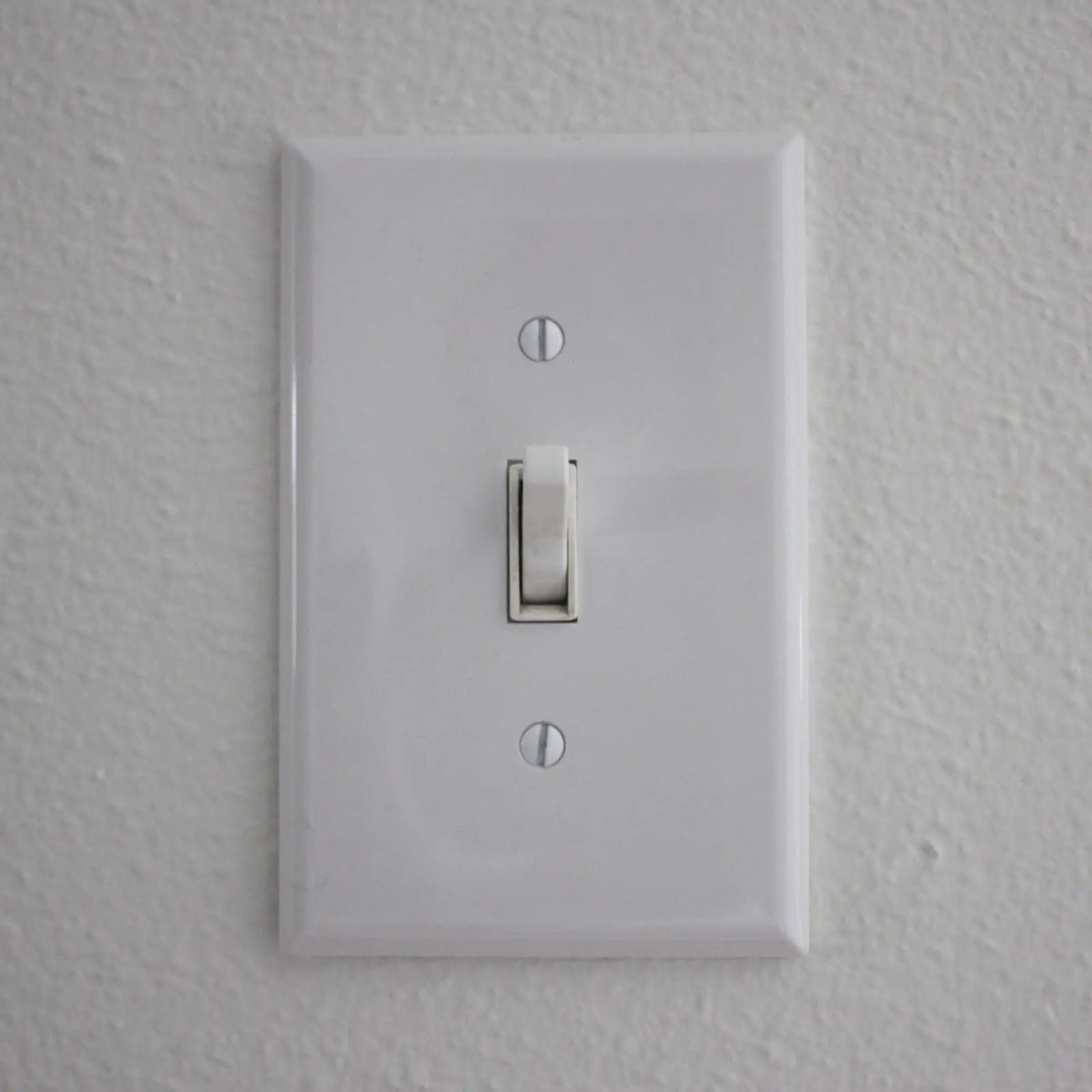 A white toggle light switch on a textured wall